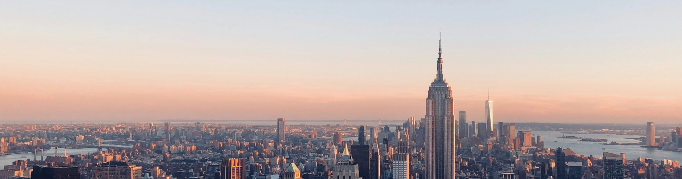 The New York City skyline at sunset, with the Empire State Building in the foreground.