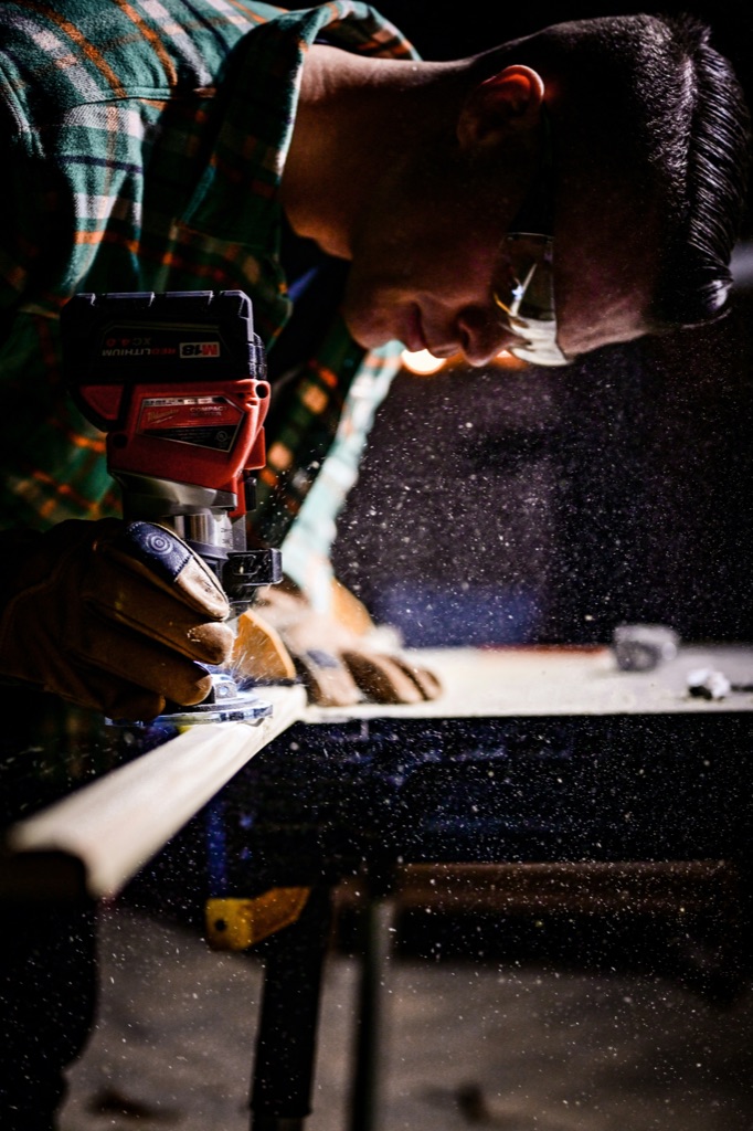 A carpenter guiding a router along a board
