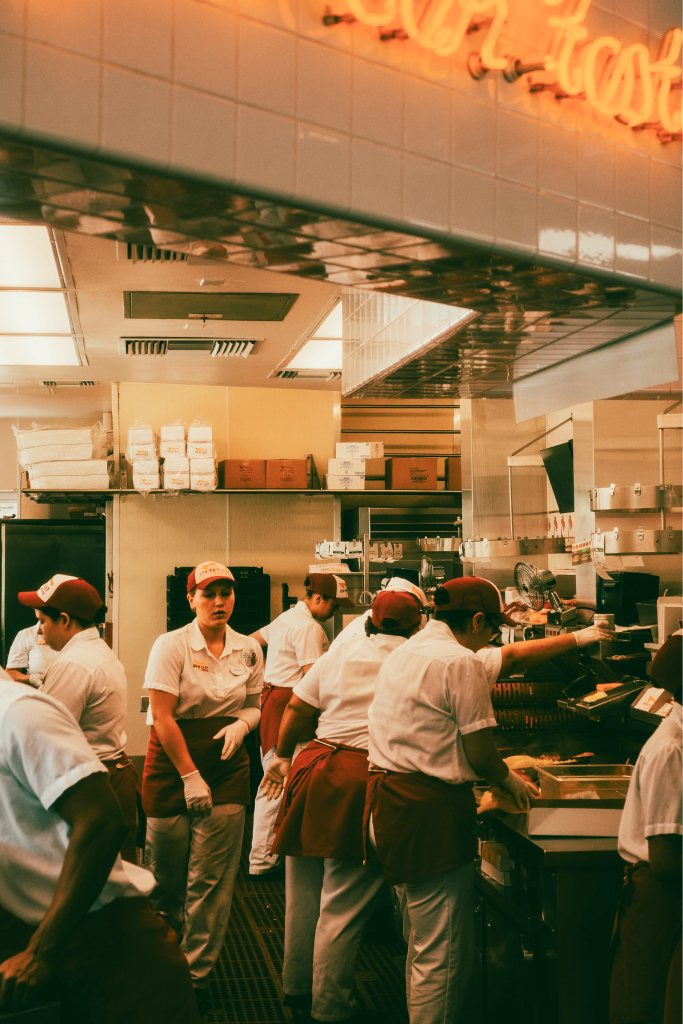 A quick-service kitchen line at work under a neon sign